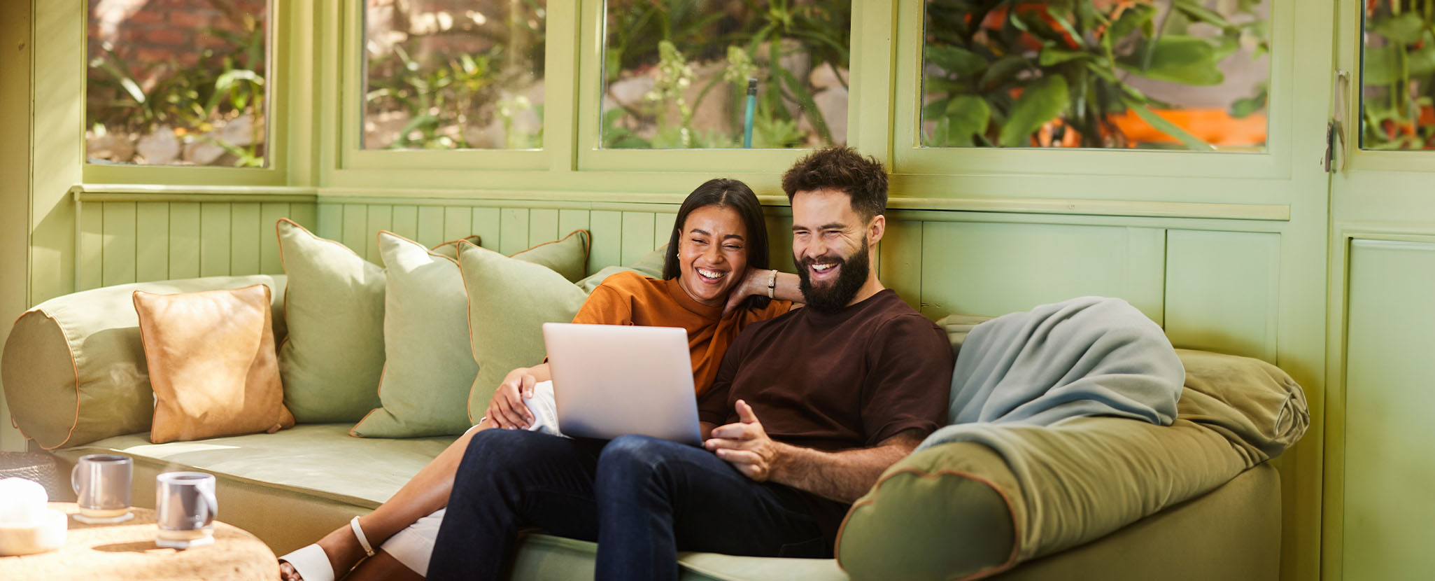 Casal feliz a simular crédito habitação no sofá.
