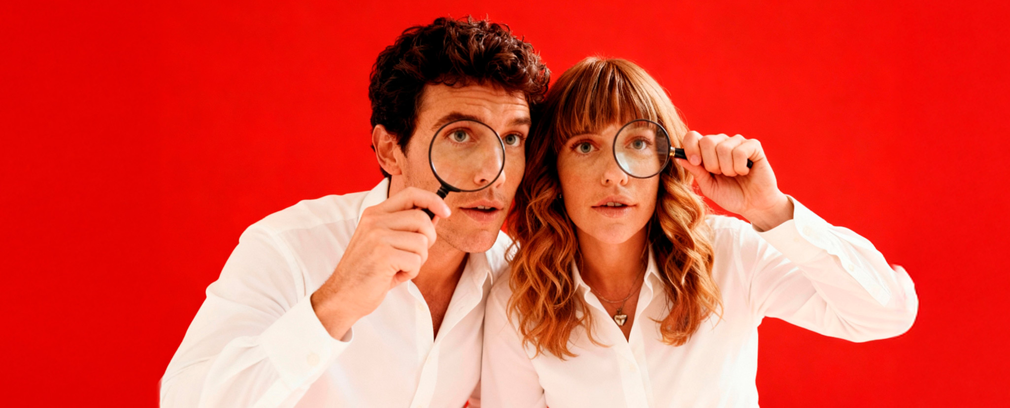 homem e mulher a espreitarem por uma lupa cada