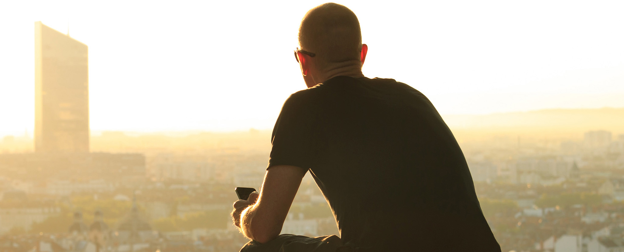 homem de costas a contemplar horizonte de cidade