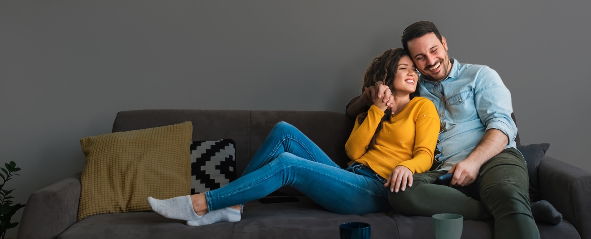 casal abraçado e sorridente num sofá