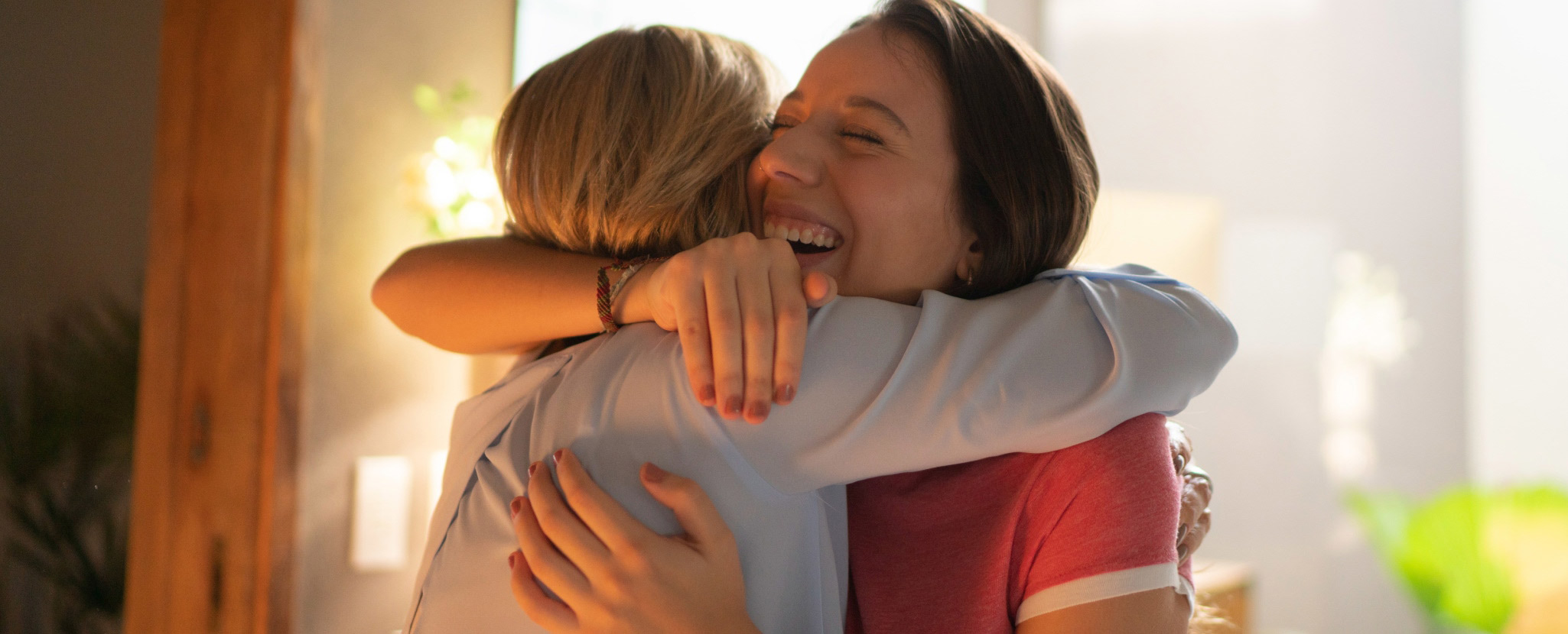 duas mulheres abraçadas, uma muito sorridente e de olhos fechados