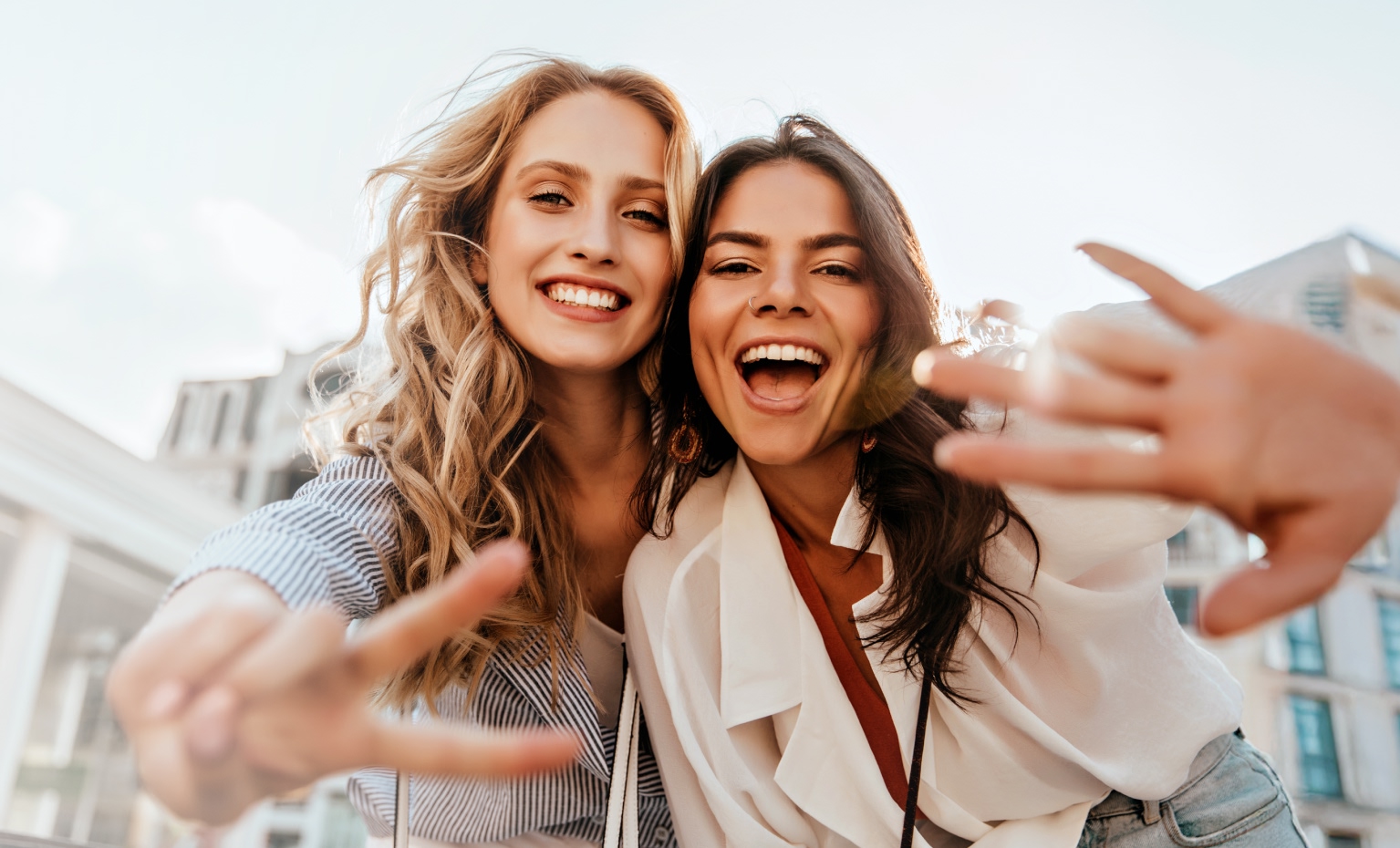 duas jovens mulheres sorridentes a posar para câmara