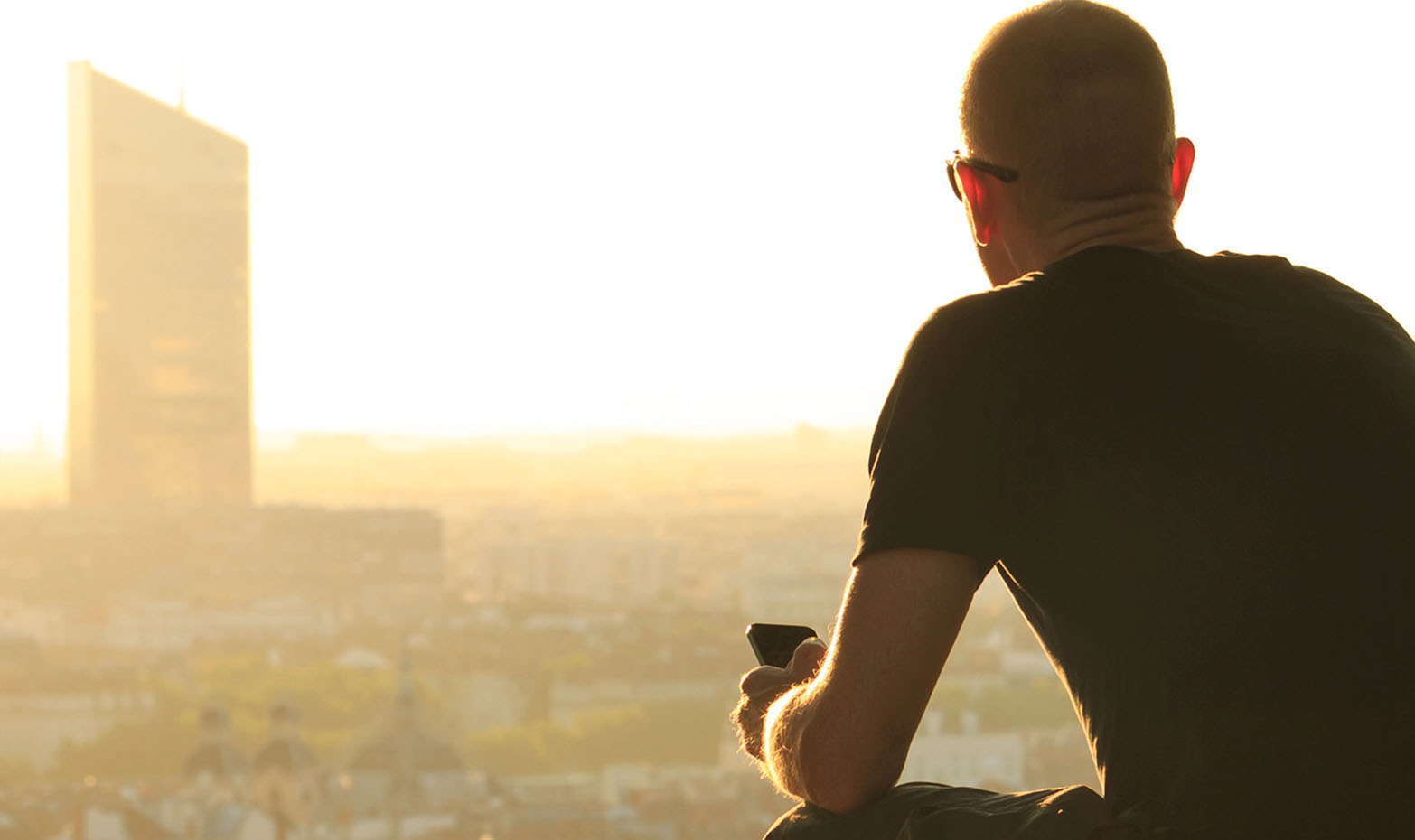 homem de costas a contemplar horizonte de cidade