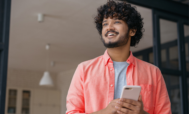 Rapaz sorridente com telemóvel na mão