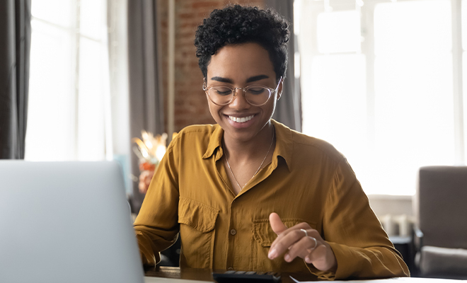 mulher sorridente em frente a um computador portátil