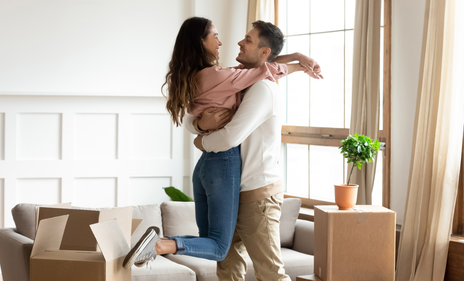 Casal jovem abraçado dentro da sua habitação após conseguir financiamento